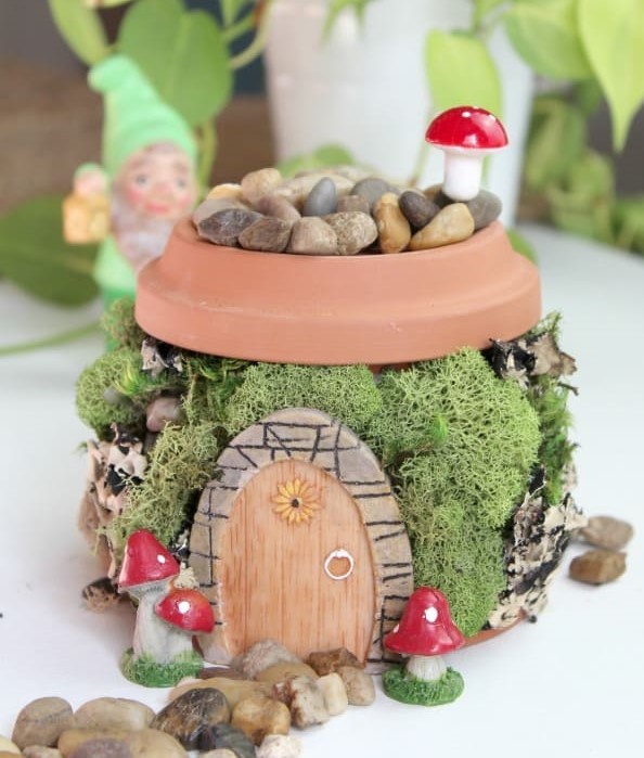 Fairy House Picture. An upside down terracotta pot with miss and rocks and a door. 