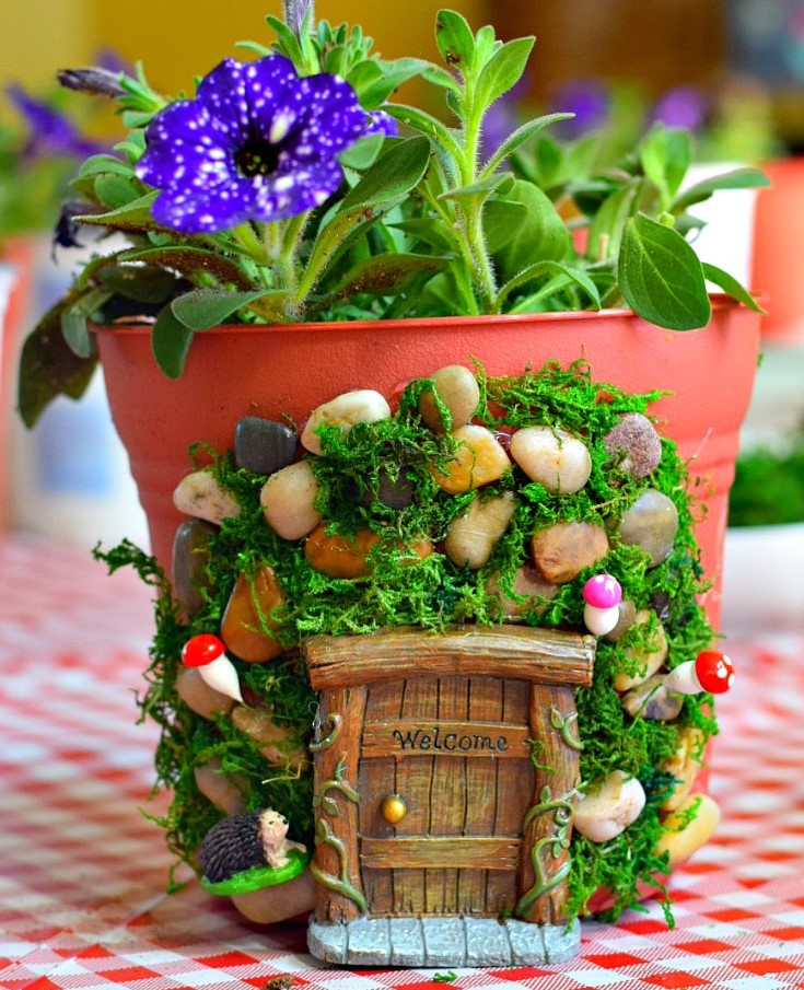 A flower pot decorated with moss and stones