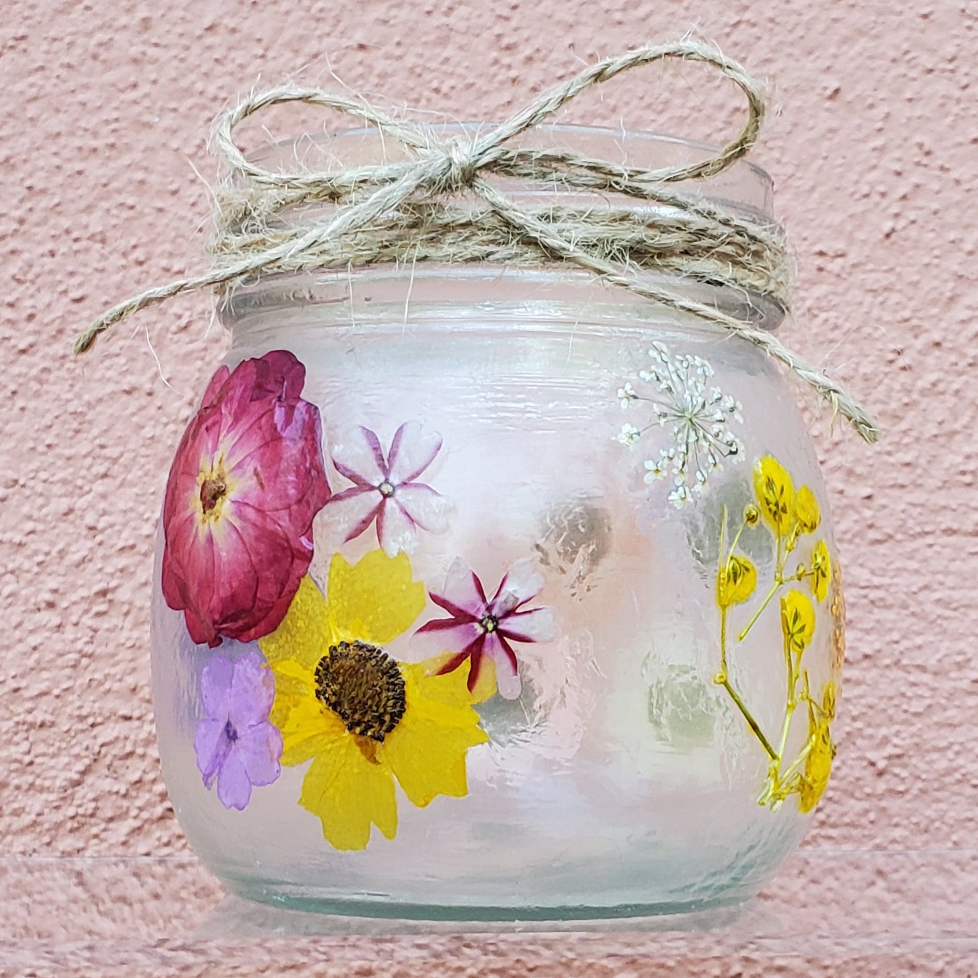 Small glass jar with pressed flowers and twine bow