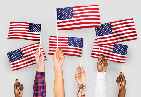 Six hands holding American flags against a white background